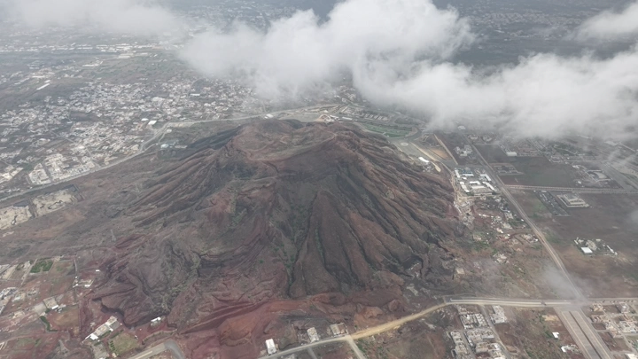 جبل الحيلة البركاني في محافظة محايل عسير محاط بالسحاب، لقطة جوية.