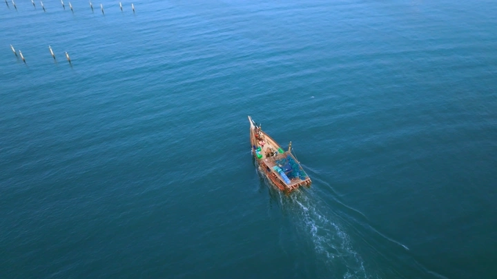 قارب خشبي يتحرك في مياه ميناء جازان، تصوير درون.