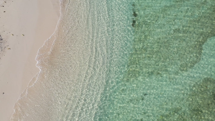 A sandy beach and clear blue waters in the Asir region, aerial shot.