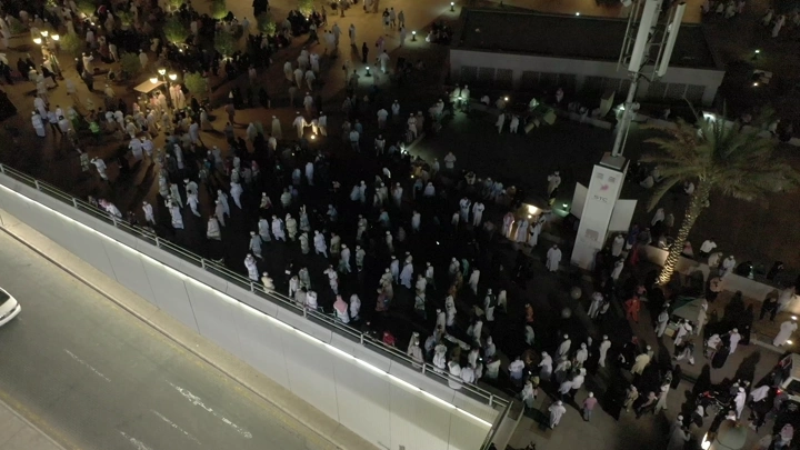 Crowd of people at Al-Masjid an-Nabawi in Medina, night aerial shot.