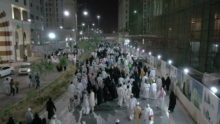 Crowd of people walking at night near Al-Masjid an-Nabawi, aerial view.