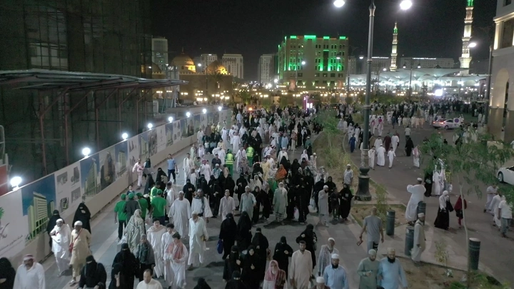 Crowd of people at Al-Masjid an-Nabawi in Medina at night, aerial shot.