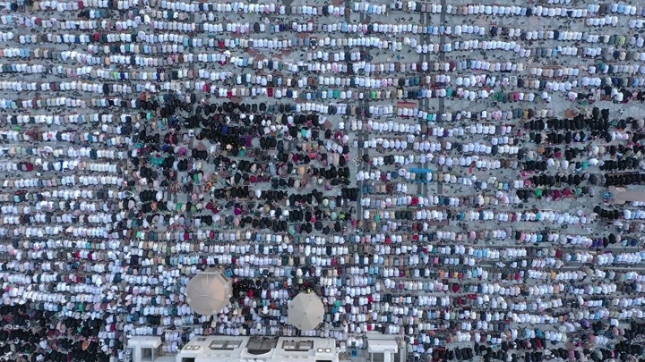 Crowds praying at Al-Masjid an-Nabawi in Medina, aerial shot.