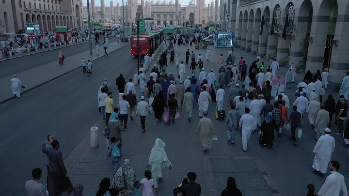 Crowds of people walking towards Al-Masjid an-Nabawi in Medina, aerial shot.
