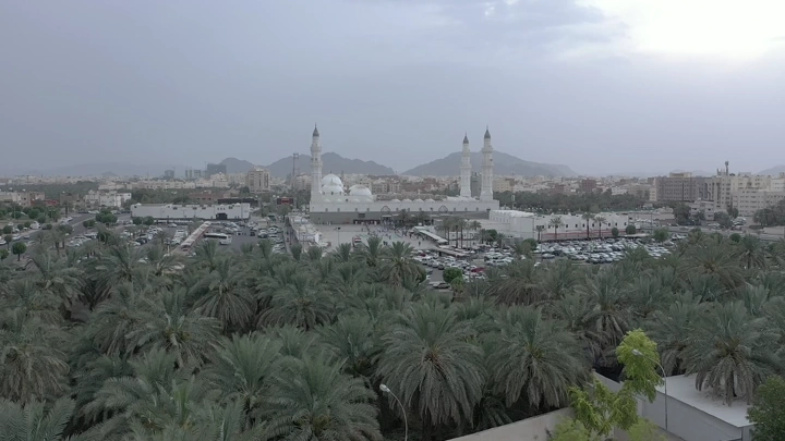 مسجد قباء في المدينة المنورة محاط بأشجار النخيل، لقطة جوية.