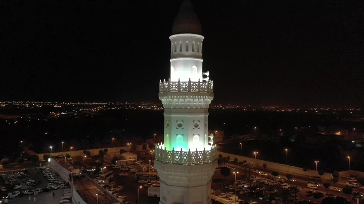 Minaret of Quba Mosque illuminated at night in Medina, aerial shot.