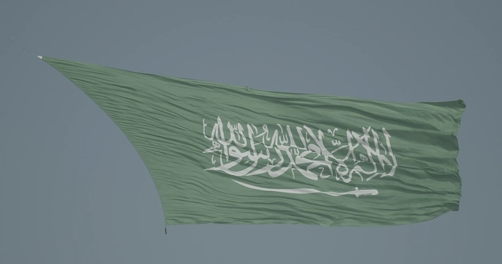 Large Saudi flag waving in the sky, daytime shot.
