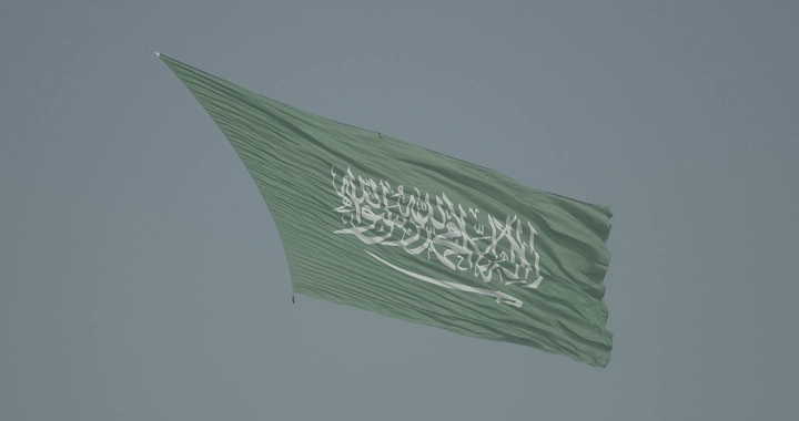 علم سعودي كبير يرفرف في السماء خلال عرض جوي، لقطة قريبة.