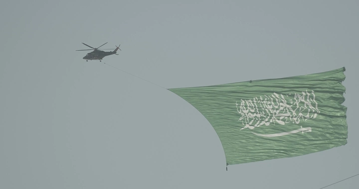 Helicopter carrying Saudi flag in the sky during National Day, wide shot.