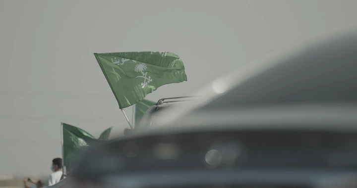 Saudi flag waving on a car during National Day, close-up shot.