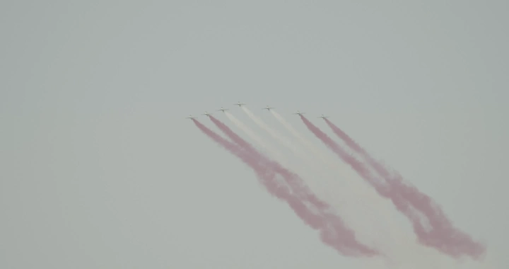 Planes releasing colored smoke in an air show, ground shot.