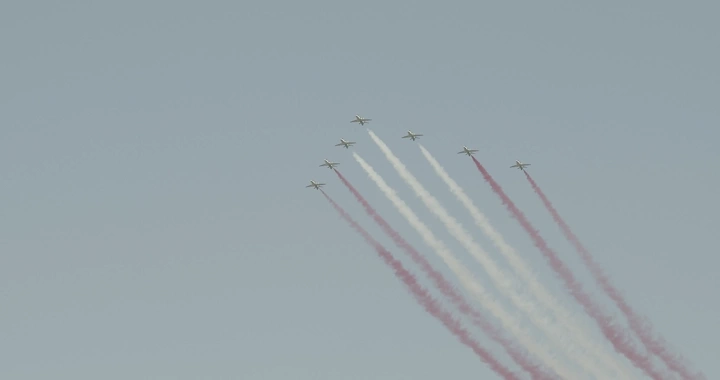 Planes releasing colored smoke in an air show, ground shot.