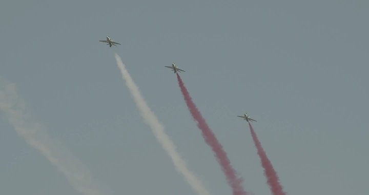 Planes releasing colored smoke in an air show, ground shot.