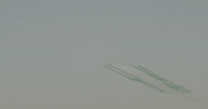 Planes in an air show with colored smoke, distant shot.