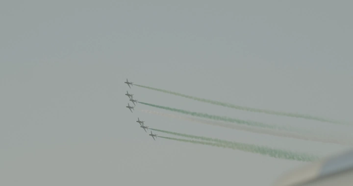 Planes releasing green smoke in an air show, ground shot.