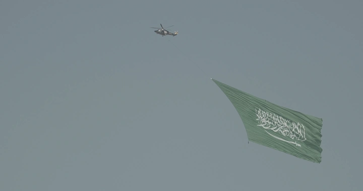 Helicopter carrying a large flag in the sky, daytime shot.