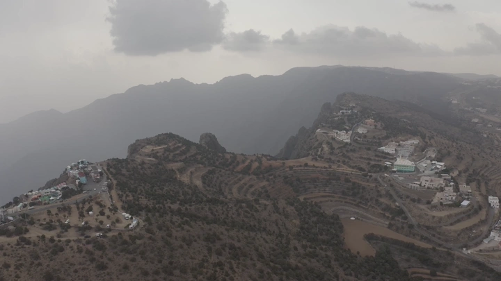 An aerial view of Al-Sahab Park in Abha, showing the mountains and clouds.