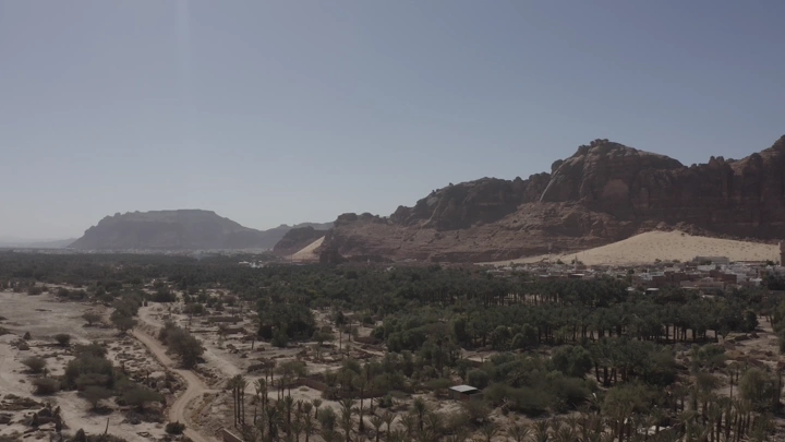 Aerial view of AlUla Old Town with mountains in the background, daytime shot.