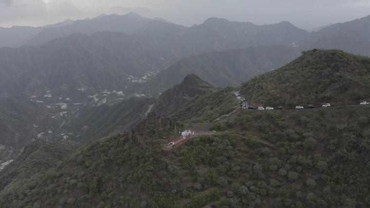 Aerial view of the mountains of Rijal Alma with an old castle appearing in the Asir region, drone shot.