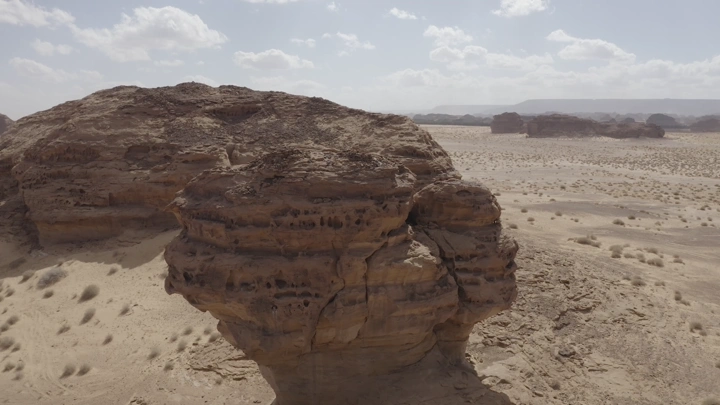 Large rock formation in AlUla under clear sky, aerial shot.