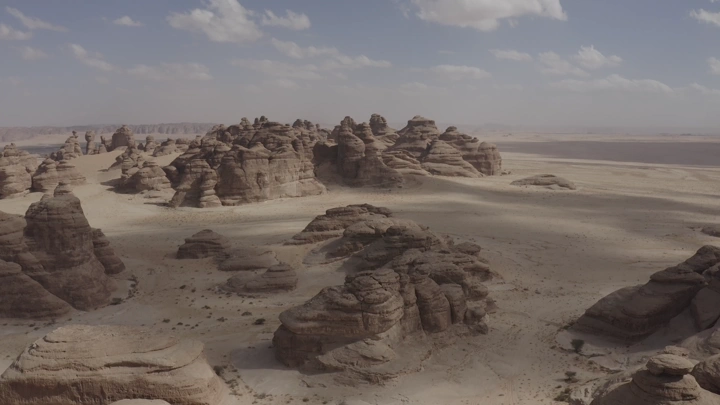 Rock formations in AlUla mountains under clear sky, aerial shot.