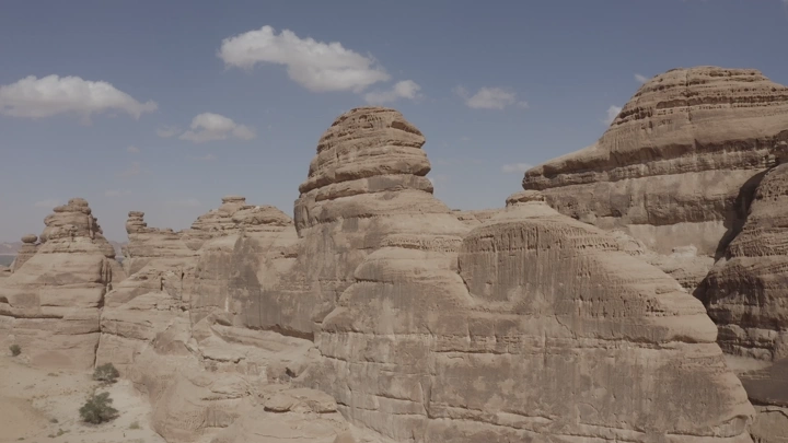 Rock formations in AlUla mountains under clear sky, aerial shot.
