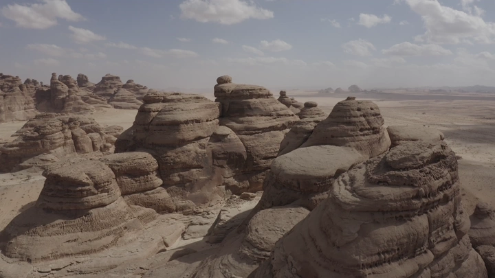 تكوينات صخرية في جبال العلا تحت سماء غائمة، لقطة جوية.