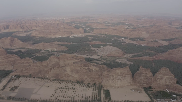 Aerial view of AlUla mountains and farms in early morning.