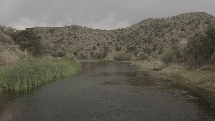 Dhubai Dam in Abha surrounded by hills and vegetation, natural shot.