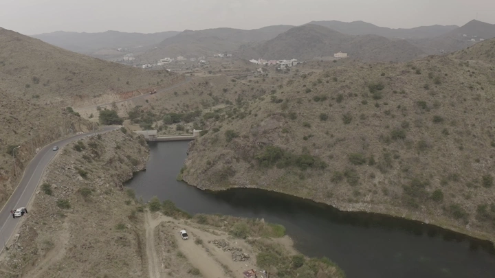 منظر جوي لسد ضبوعي في أبها، محاط بالتلال والطرق.