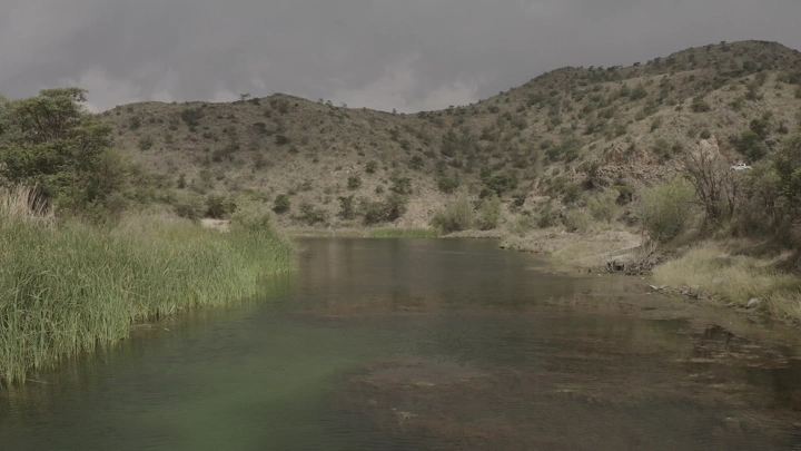 Dhubai Dam in Abha surrounded by hills and vegetation, daytime shot.
