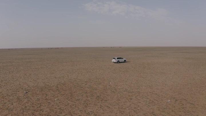 Car in northern desert landscape, aerial shot.