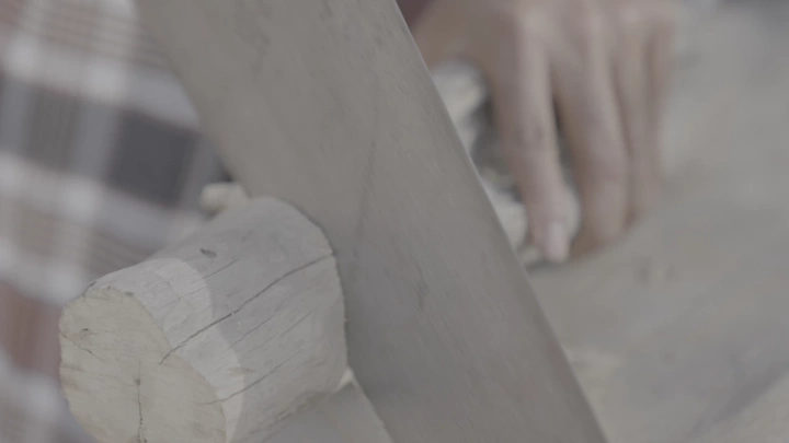 نجار يعمل على قطعة خشب بمنشار، لقطة قريبة.