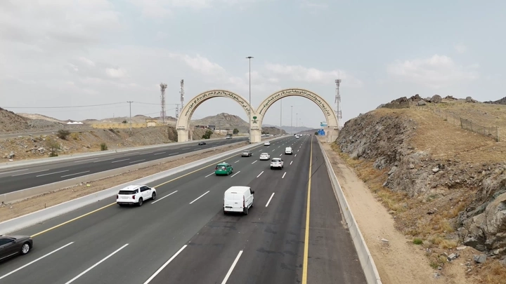 طريق سريع مزدحم في مكة مع قوسين في الخلفية، لقطة جوية.
