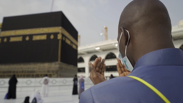 شخص يدعو أمام الكعبة في الحرم المكي، لقطة قريبة.