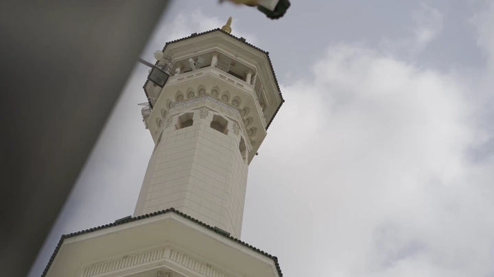 منارة الحرم المكي تحت السماء الغائمة، لقطة من الأسفل.