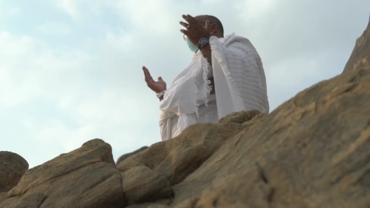 شخص يرتدي إحرامًا على جبل، لقطة من زاوية منخفضة.