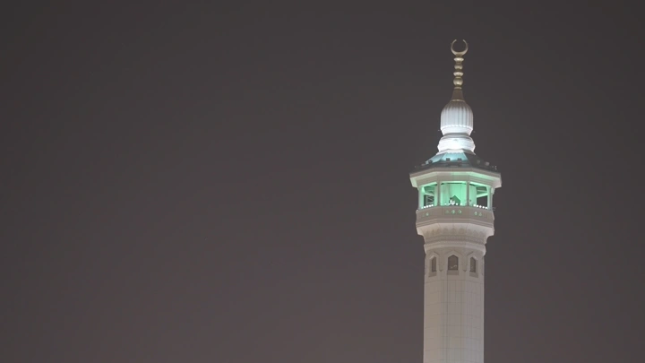 مئذنة مضاءة في الليل، لقطة قريبة.