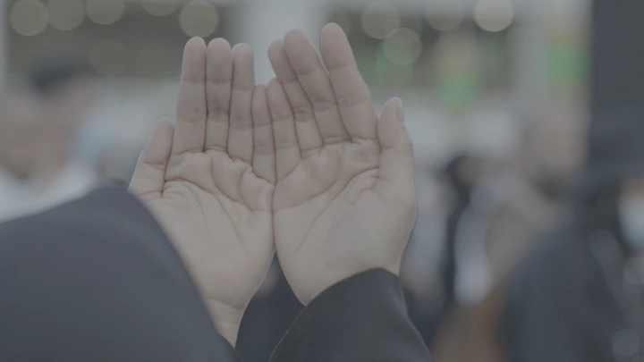 يدان مرفوعتان بالدعاء في الحرم، لقطة قريبة.