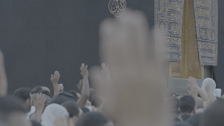الحجاج يرفعون أيديهم أمام الكعبة في مكة، لقطة قريبة.
