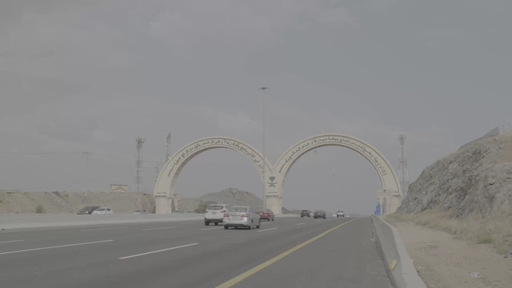طريق سريع يؤدي إلى مكة مع بوابة ترحيبية، لقطة نهارية.
