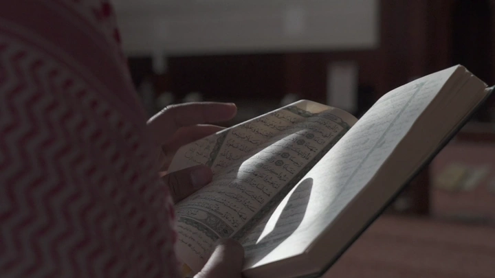 شخص يقرأ القرآن في مسجد، لقطة مقربة.