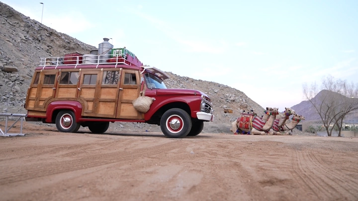 شاحنة حمراء وجمال في الصحراء، لقطة منخفضة.