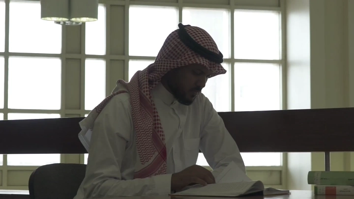 طالب يدرس في مكتبة جامعة، لقطة جانبية.