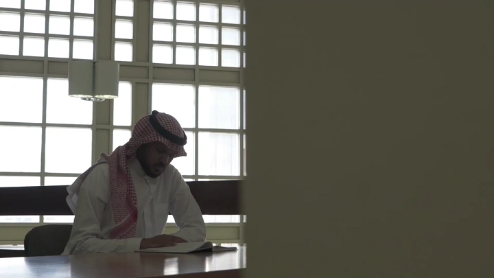 طالب يدرس في مكتبة جامعة، لقطة داخلية.