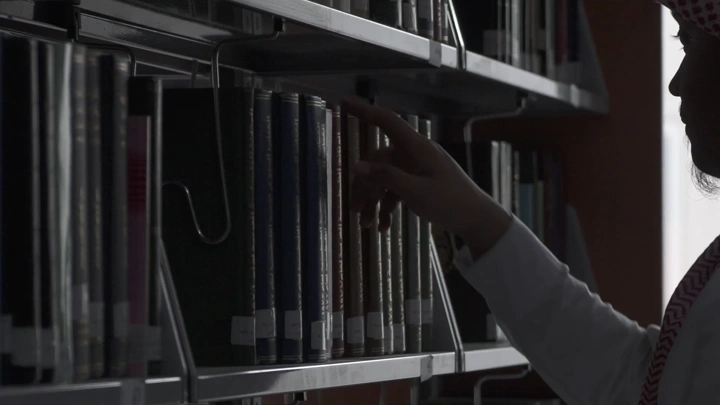 شخص يبحث عن كتاب في مكتبة جامعية، لقطة جانبية.