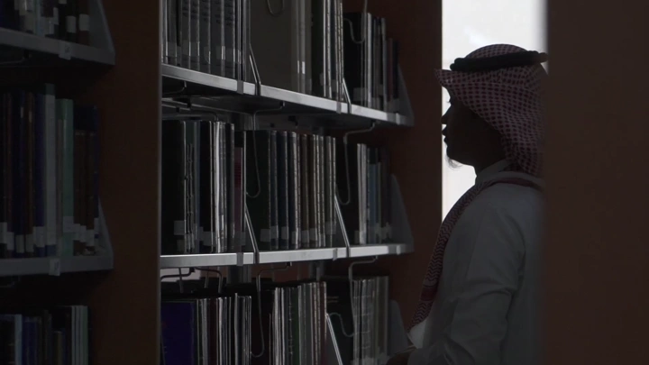 طالب يقف في مكتبة جامعة، لقطة ظلية.