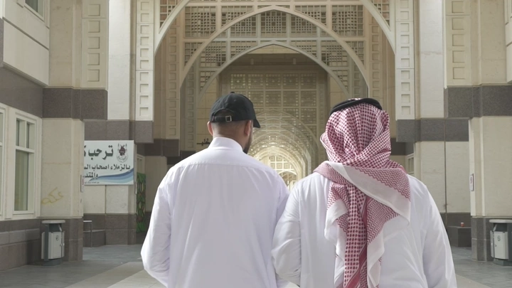 شخصان يسيران في ممر جامعة، لقطة من الخلف.