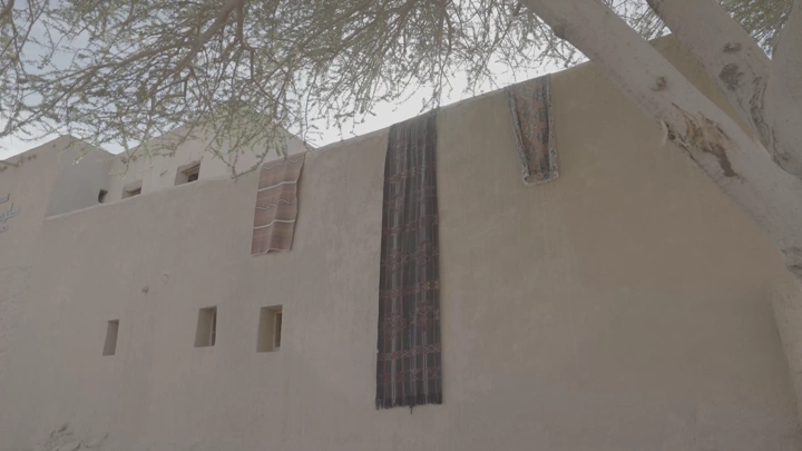 أقمشة تقليدية معلقة على جدار طيني في العلا، لقطة من الأسفل.