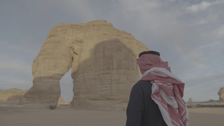 رجل يرتدي الزي التقليدي أمام صخرة الفيل في العلا، لقطة واسعة.